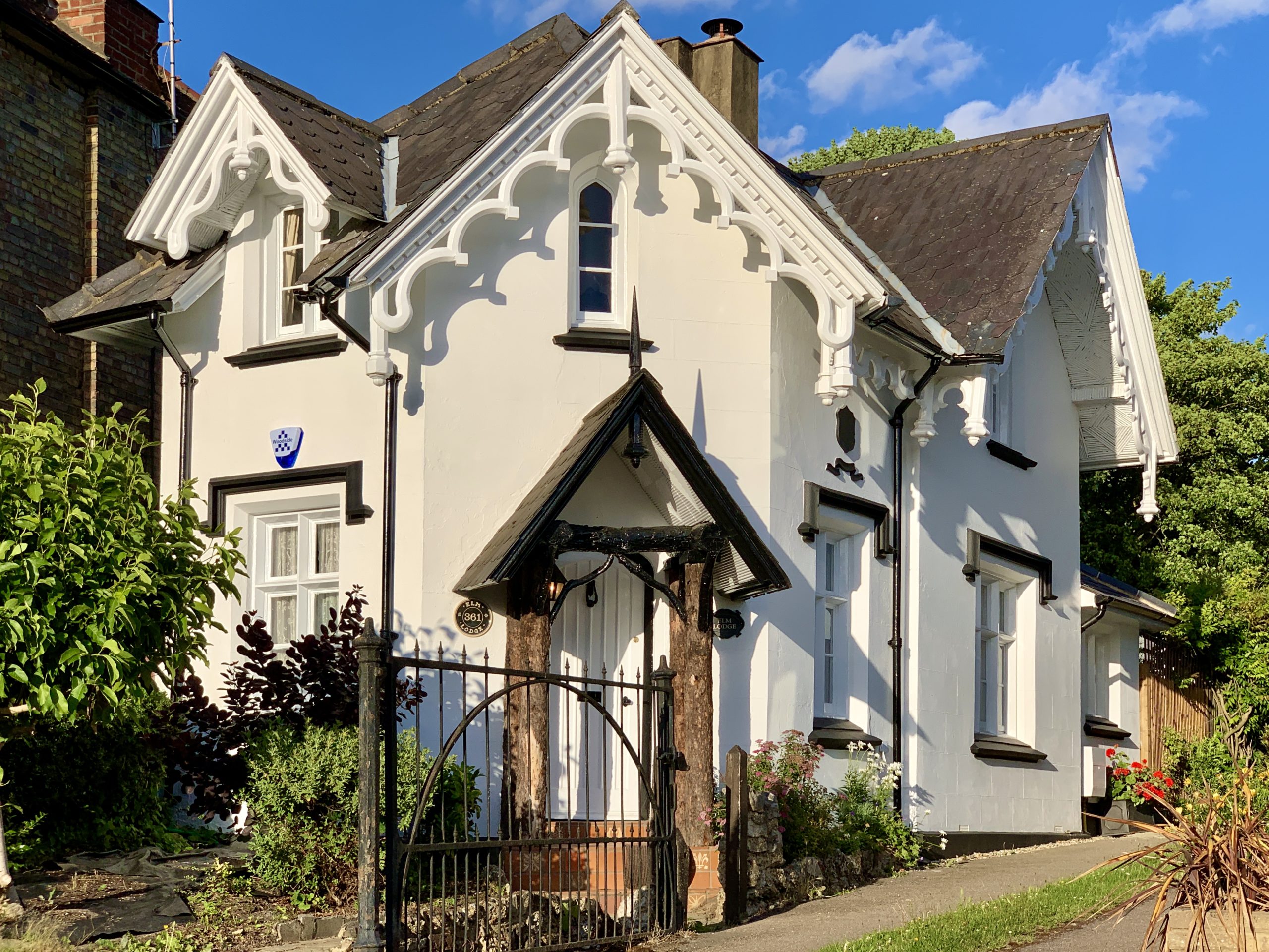 house with ornamented roof and covered entrance area in a foresty setting.